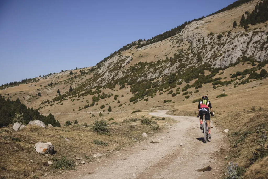 Participante empujando su bicicleta en una subida exigente del Pirineo
