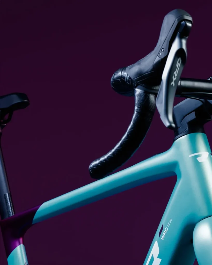 Detalle del manillar con grupo Shimano GRX de la Conor E‑SELVA y parte frontal del cuadro en acabado turquesa con gráficos minimalistas