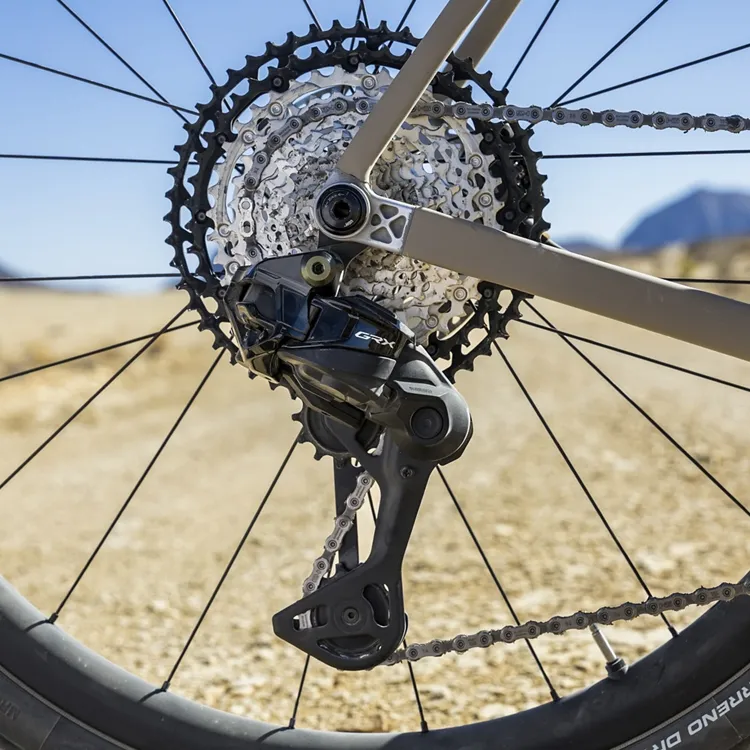 Vista trasera del desviador Shimano GRX Di2 827 de 12 velocidades instalado en una bicicleta, en un entorno desértico. Se aprecia el cassette de amplio rango y el sistema de transmisión listo para el ciclismo off-road.