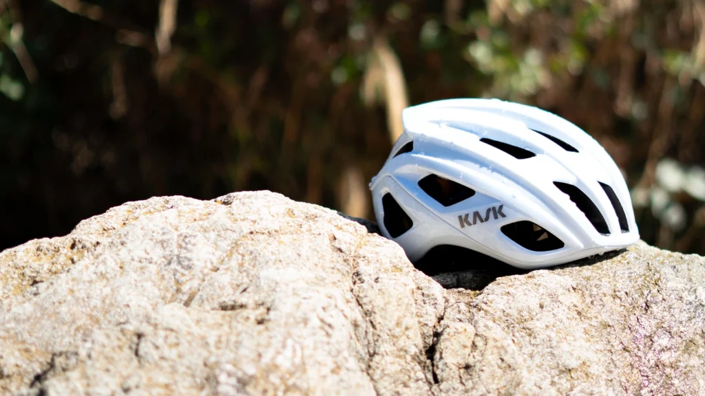 Casco Kask Mojito blanco apoyado sobre una roca en exterior